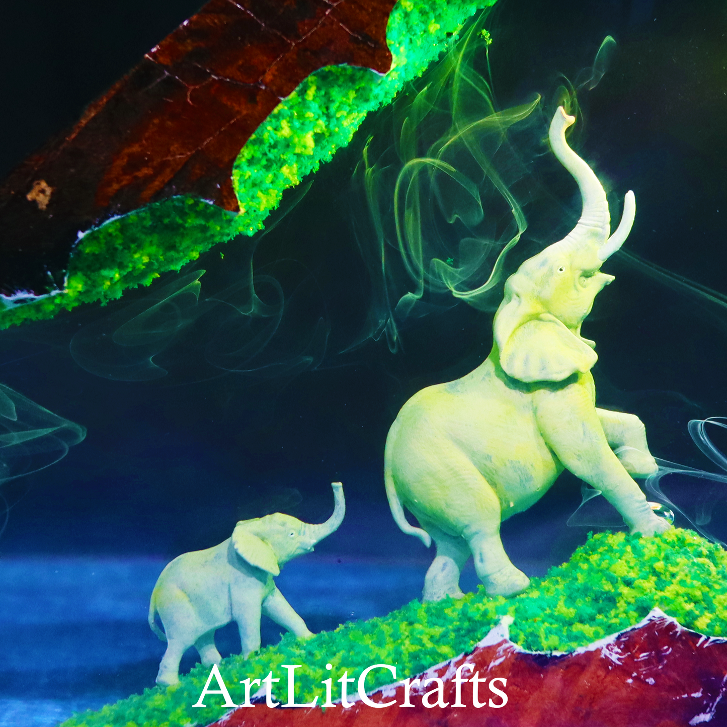 close up of elephant and calf miniature inside handcrafted epoxy resin lamp on a colorful background with 'ArtLitCrafts' branding.