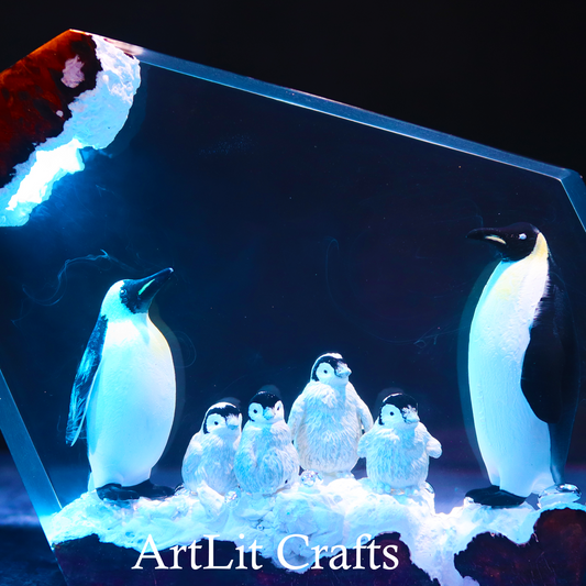 close up view of penguin parents and chicks inside resin lamp with 'ArtLit Crafts' branding