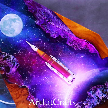 Close up galaxy resin lamp glowing with purple ambient lighting, featuring the brand 'ArtLitCrafts'.
